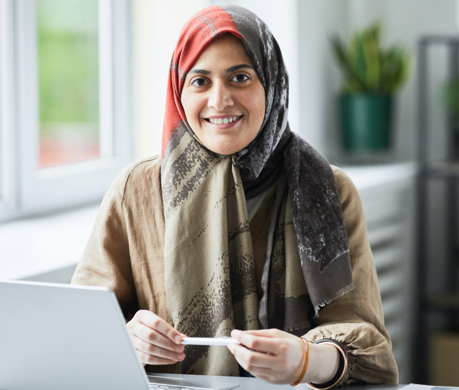 Smiling muslim women sitting at a desk with the laptop open