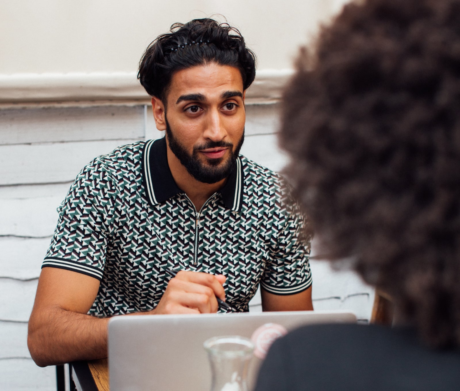 Young male sat at a desk in communication with another person