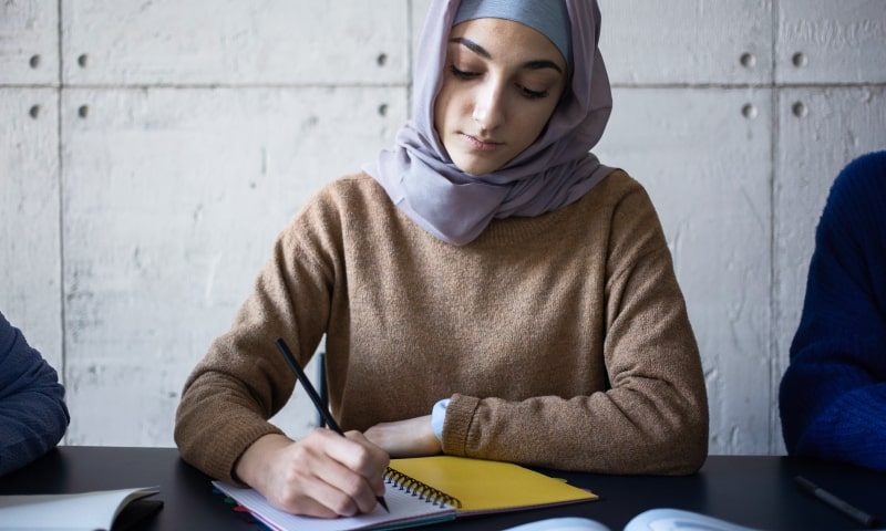 Women attending a class and sat at a desk writing